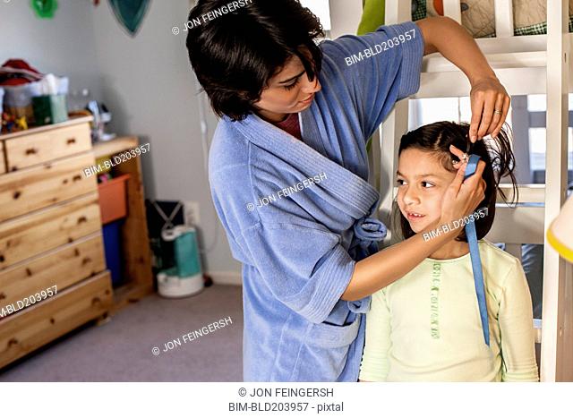 Hispanic mother brushing daughter's hair