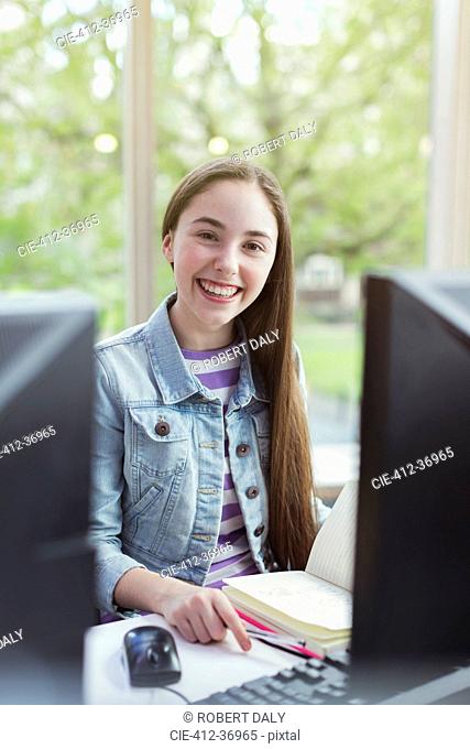 Portrait smiling, confident girl student researching at computer in library