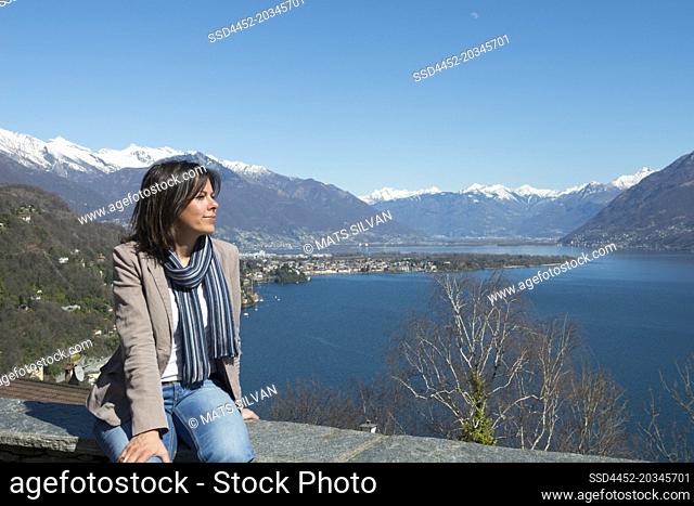 Woman Sitting and Enjoy the Panoramic View over Alpine Lake Maggiore with Snow-capped Mountain in Ascona, Switzerland