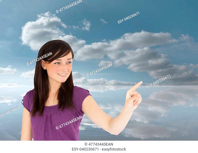 Composite image of attractive brunette pointing something with her finger in the cloudy sky