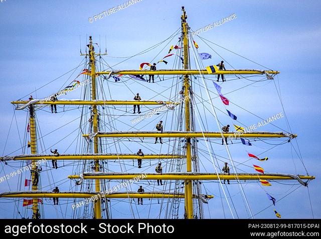 12 August 2023, Mecklenburg-Western Pomerania, Rostock: At the 32nd Hanse Sail sailors stand in the shrouds of the 111-meter-long sail training ship of the...