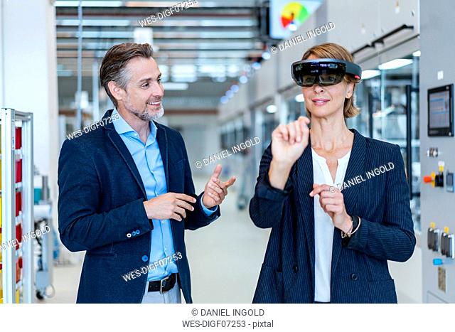 Businesswoman with AR glasses and businessman in a modern factory
