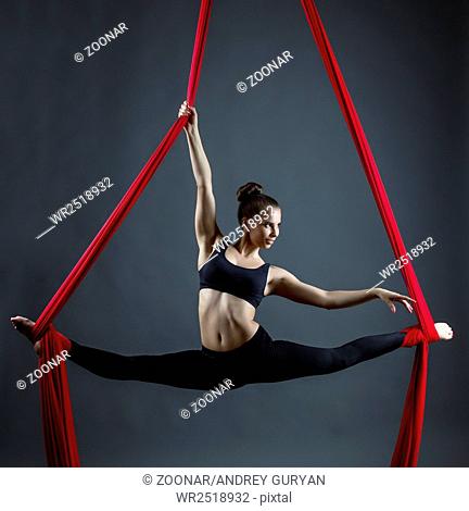 Flexible young woman dancing using hanging ribbons