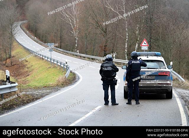 31 January 2022, Rhineland-Palatinate, Mayweilerhof: Police officers stand at a barricade on county road 22 about a kilometer from the scene where two police...
