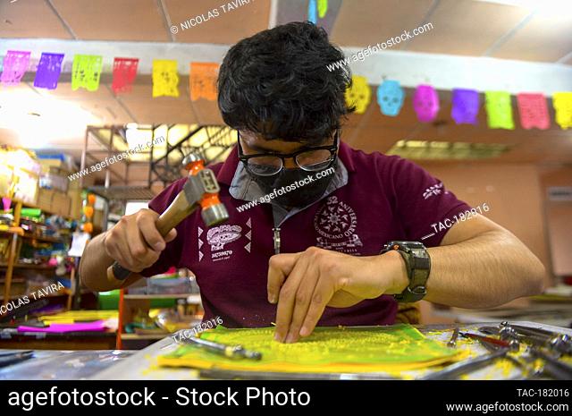 MEXICO CITY, MEXICO - OCTOBER 21: A worker from the ""Taller de Yuriria"" wears a protective mask, while using a template to cutting a traditional Mexican paper...