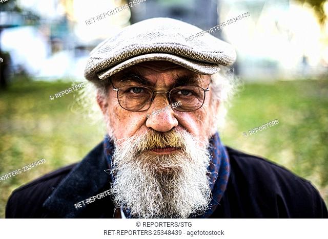 Belgium , Brussels , Nov 24 , 2017 - Homme retraité assis sur un banc - Solitaire -Fumant une cigarette - Lisant le journal - Homme devant un lac - Seul dans un...