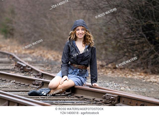 A young woman sitting on train tracks