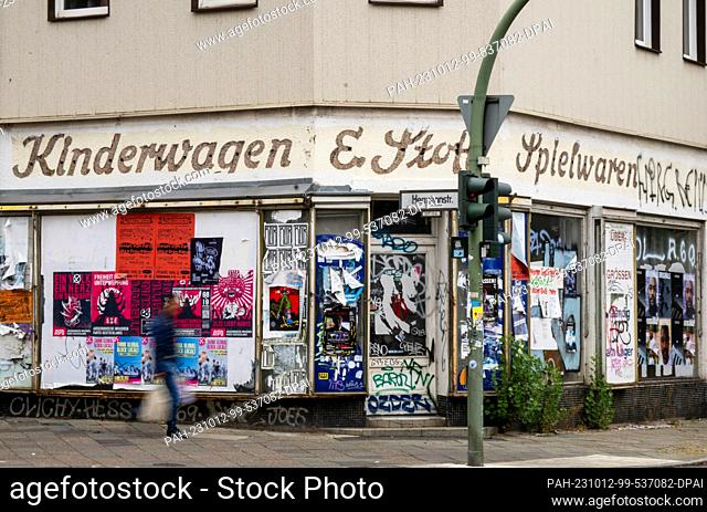 PRODUCTION - 09 October 2023, Berlin: A man walks past an abandoned former store in need of renovation in the Neukölln district