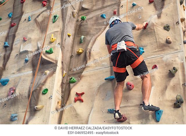 Young man practicing rock climbing on artificial wall indoors