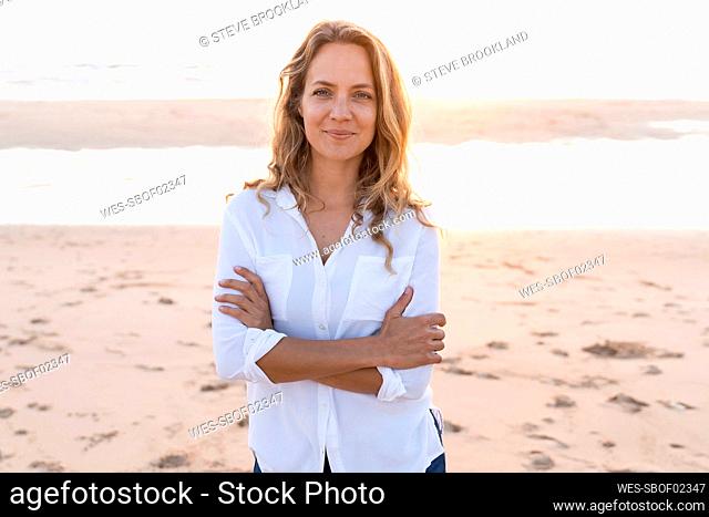 Smiling woman standing with arms crossed at beach