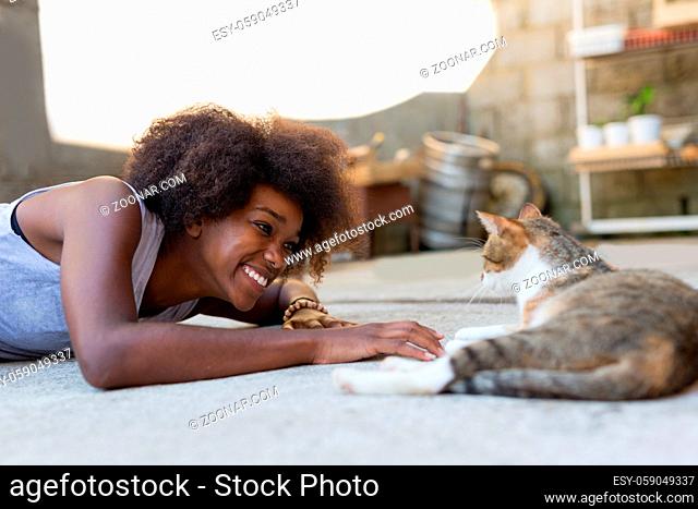 Beautiful afro american woman with her cat on the terrace. Concept of spending time with our pets and relax time