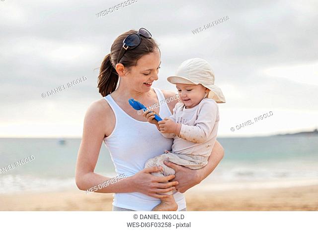 Mother holding little daughter on the beach