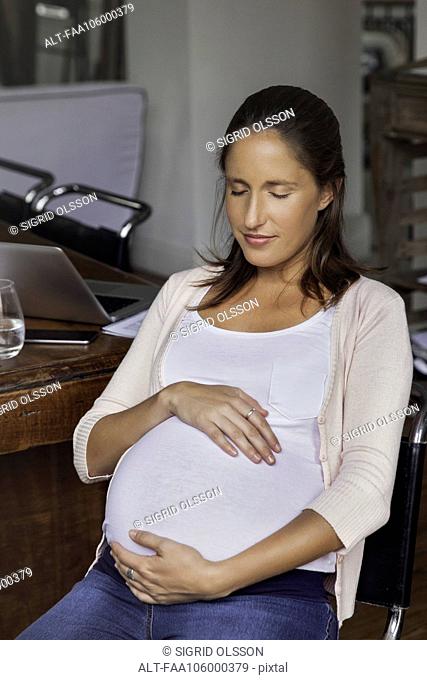 Pregnant woman cradling belly, portrait