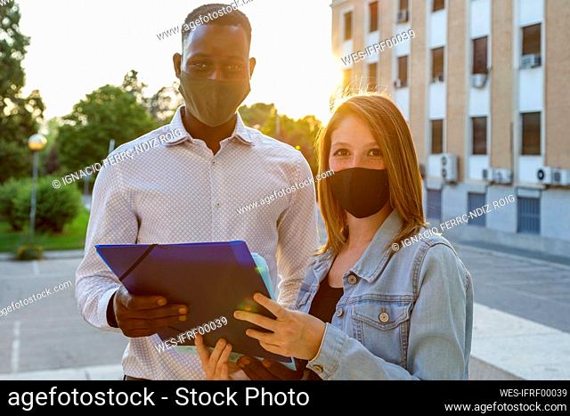 Male with female university student wearing protective face mask while standing in campus