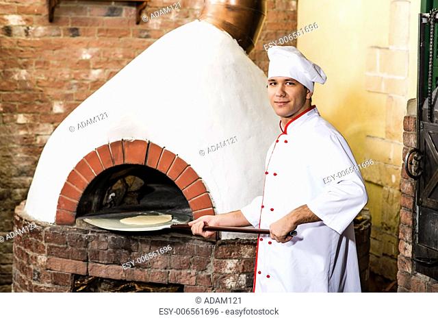 Chef puts dough in the oven for pizzas, traditional cooking