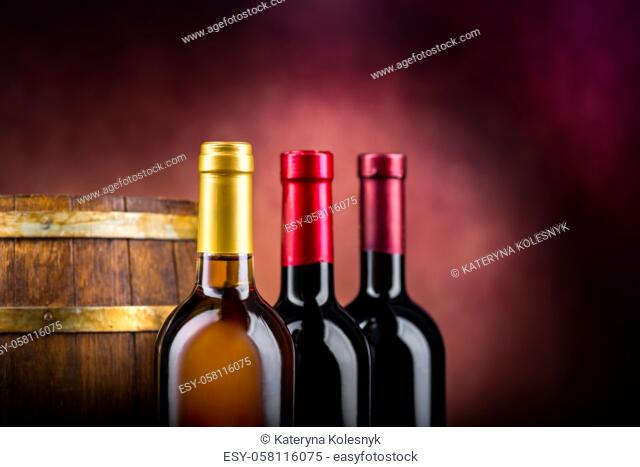 Three bottles of wine and wooden barrel on a burgundy background