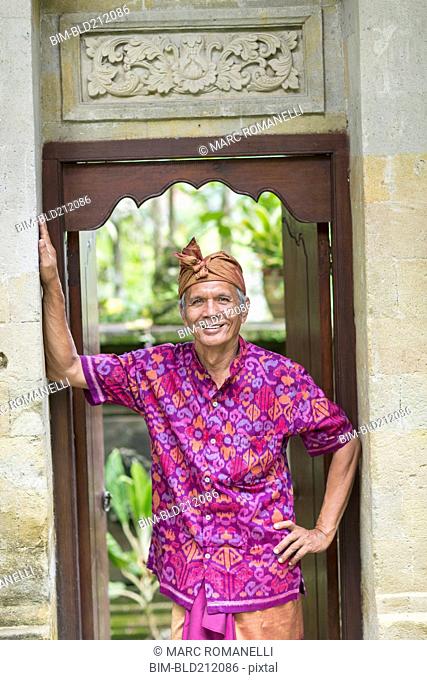 Balinese worker smiling in wood archway