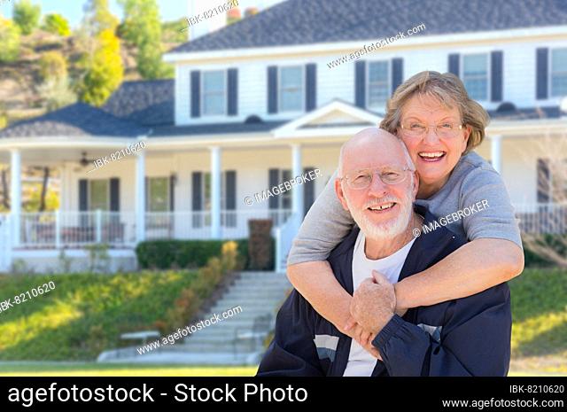 Attractive happy senior couple in front yard of house