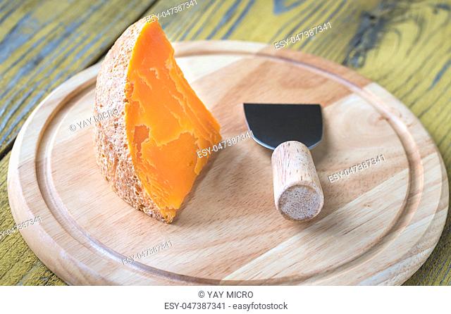 Wedge of Mimolette cheese on the wooden board