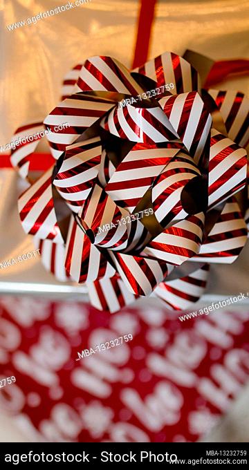 Christmas gifts stacked, wrapping paper with Hohoho inscription and a large red and white bow