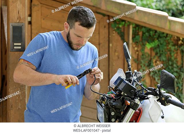 Young man repairing enduro motorcycle