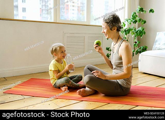 Mother and daughter having fruit and drink at home