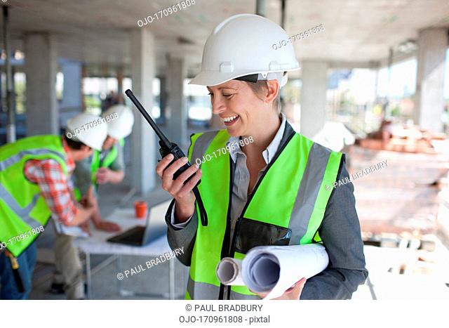 Businesswoman talking on walkie talkie on construction site