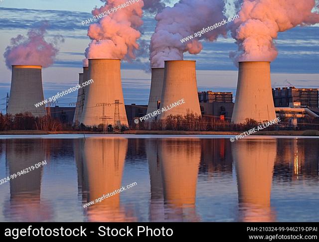 22 March 2021, Brandenburg, Jänschwalde: The warm light of the low evening sun shines on the cooling towers of the Jänschwalde lignite-fired power plant...