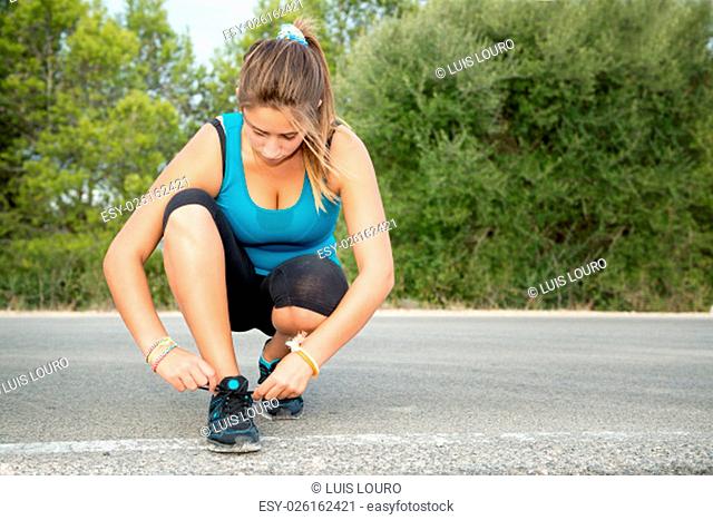 Youg woman jogger tying hers shoes outdoors