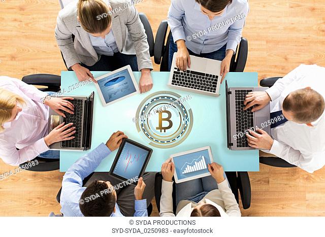 business team with computers and bitcoin hologram