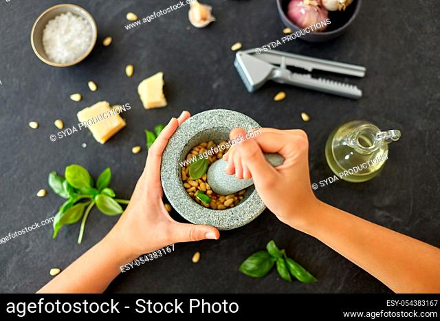 hands grinding pine nuts in mortar and pestle