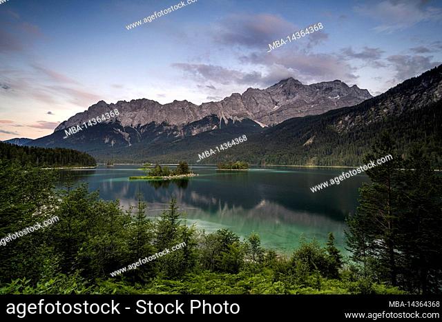 The Eibsee and the Zugspitz massif after sunset with soft colors and in the foreground the lake with its small islands