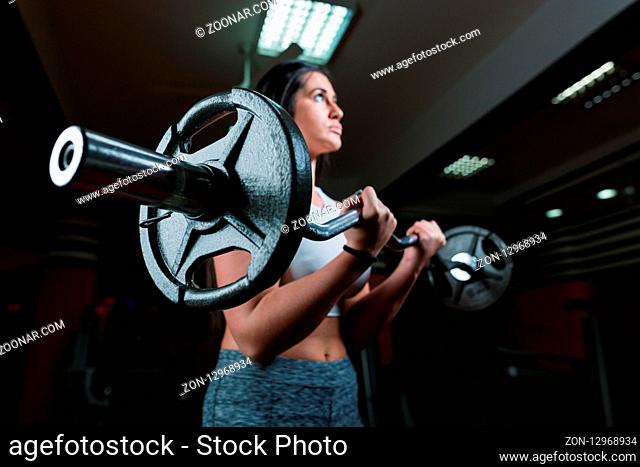 Strong young woman with beautiful athletic body doing exercises with barbell. Fitness, bodybuilding. Health care