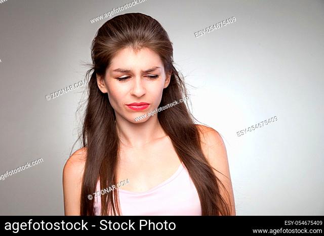 Upset woman feeling her guilty. With some contempt on her face. Studio portrait on grey vignette background