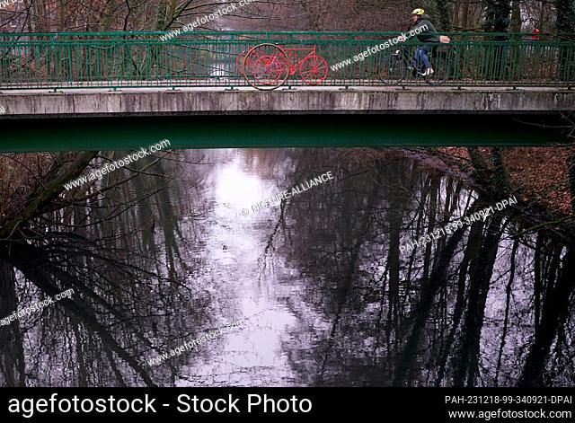 18 December 2023, Hamburg: A woman rides a bicycle across a bridge over the Isebek Canal. Photo: Marcus Brandt/dpa. - Hamburg/Hamburg/Germany