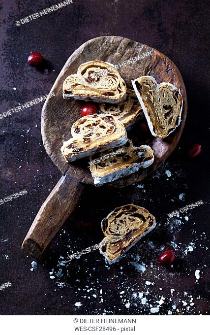 Sliced Christmas Stollen with icing sugar on a wooden scoop