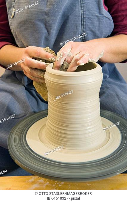 Ceramic artist working in her workshop with a potter's wheel, pulling a cylinder, Geisenhausen, Bavaria, Germany, Europe