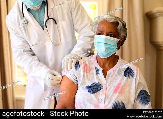 Senior african american woman in face mask receiving vaccination