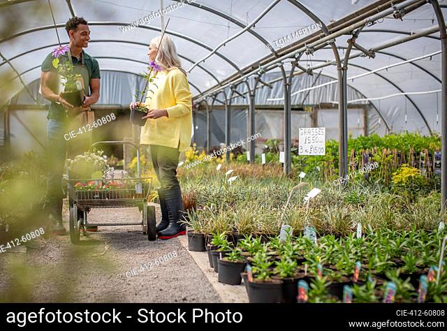 Garden shop owner helping customer with plants in greenhouse