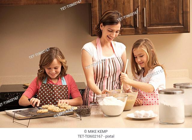 Mother baking with daughters 10-11 in kitchen