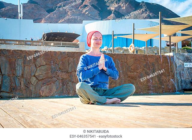 Woman doing yoga asana near pool on a hot day