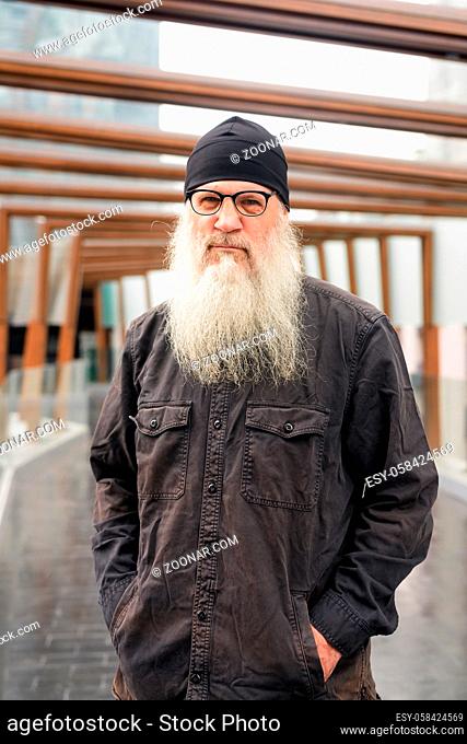 Portrait of mature handsome bearded hipster man at footbridge in the city