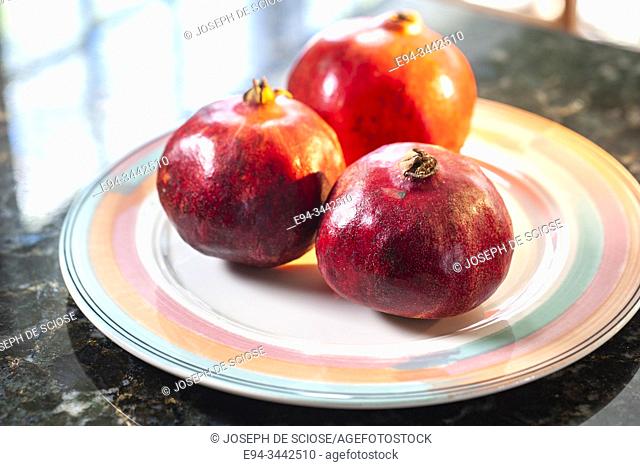 3 pomegranates on a plate in a kitchen