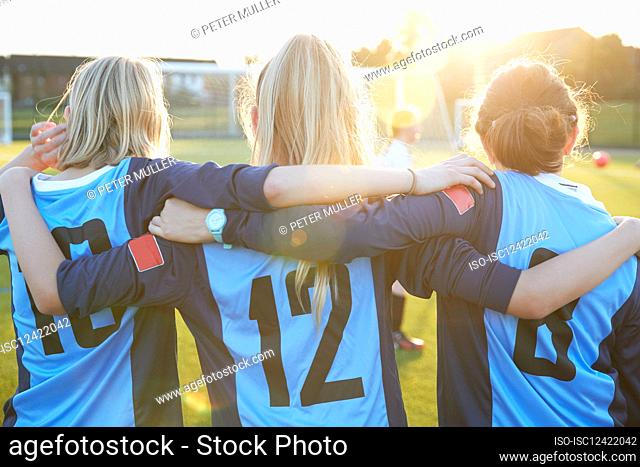 UK, Rear view of female soccer players embracing in field
