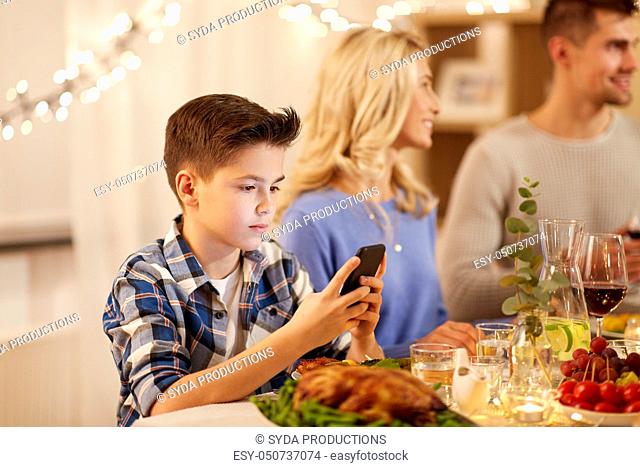 boy with smartphone at family dinner party