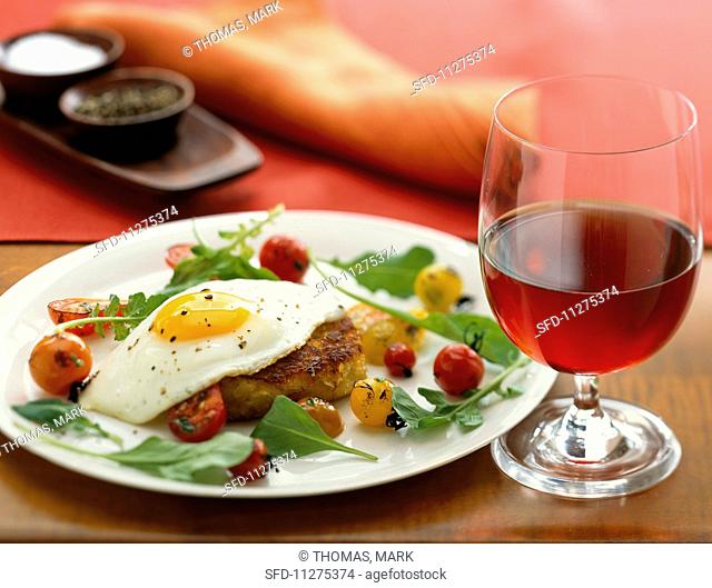 A crab cake topped with a fried egg and served with cherry tomatoes and rocket