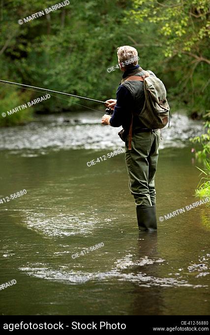 Man with backpack fly fishing at river