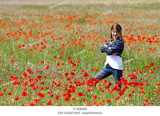 Girl on the meadow posing with lots of red poppies around her