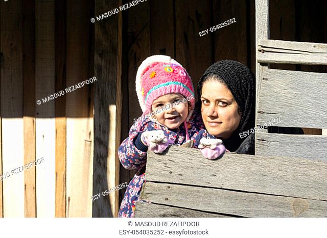 Young mother and a little girl in her hug portrait in wooden hut