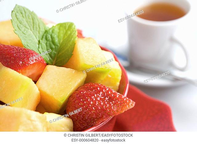 Fruit Salad in a red bowl with a cup of tea